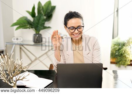 Video Meeting Concept. Cheerful Middle-aged Woman Holding Video Call On The Laptop At Office, Waving