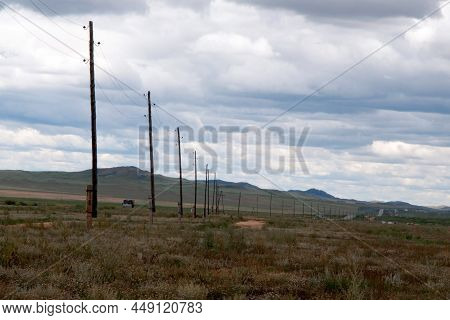 Landscape In Central Mongolia Close To The Main Road. Electricity Poles Along The Roal. Green Hills 