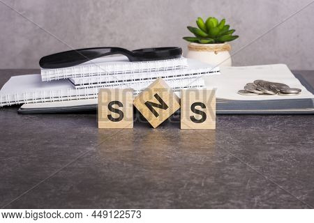 Letters Sns Written On Wooden Cubes On A Gray Background. Close-up Of Wooden Elements. In The Backgr