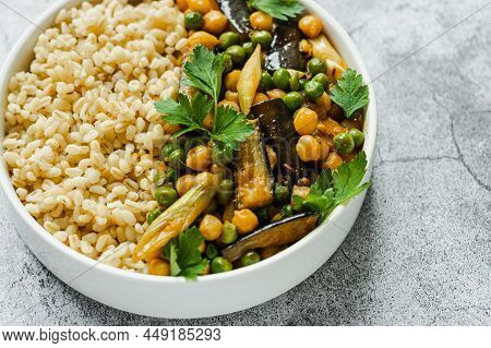 Eggplant Chickpeas Peas Vegetarian Vegan Curry With Bulgur In A Pan On A Gray Background, Top View.