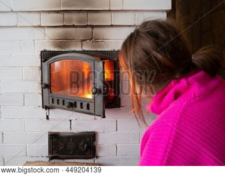 Girl Throws Firewood Into The Fire In The Stove. Furnace Firebox In The House. Lighting A Fire In Th