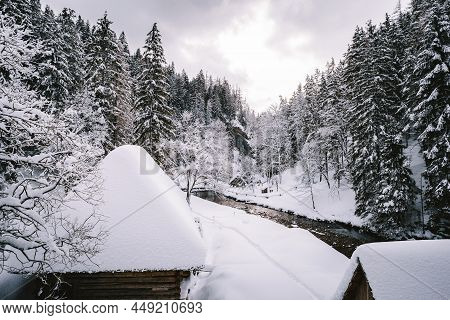 Snow Covered And Frozen Wooden Cabins In The Middle Of Mountain (forest) With Stream On Background I