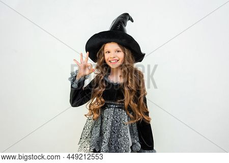 Surprised Young Witch On A White Background. The Costume Of The Sorceress For The Carnival. A Magici