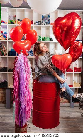 Woman On Red Decorative Barrel. With A Large Red Balloons In The Shape Of Heart.