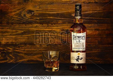 Bottle Of Dewar's Japanese Smooth 8 Years Old Scotch Whisky And A Glass With Ice On A Dark Wooden Ba