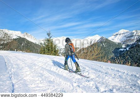 A Sporty Child Climbs The Snowy Road With Skis And Skins