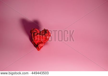 Red Heart Of Rumpled Paper On A Pink Background With Shadow. Valentine's Day Concept. A Symbol Of Se