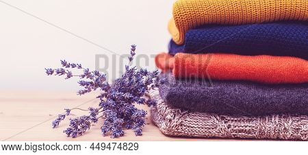 Home Wardrobe With Winter Clothes. Woolen Sweaters And Dried Lavender For Protection From Moth. Knit