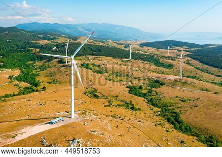 Contemporary Wind Machines Rotate Generating Clean Energy Scattered On Hill Slopes Against Forestry 
