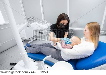 Mom And Baby At The Reception At The Pediatric Dentist. First Visit To The Dentist. Diagnosis And Tr