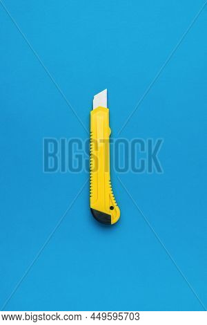 Photo Of A Minimalistic Design Of A Yellow Stationery Knife On A Blue Background. The Central Compos