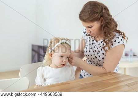 Mother Helps To Put On Cochlear Implant For Her Deaf Little Daughter. Hearing Aid And Deafness Conce
