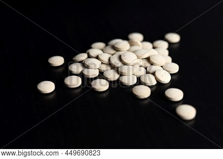 Pills Scattered On A Black Wooden Table. Background For Pharmacy, Antibiotics, Vitamins