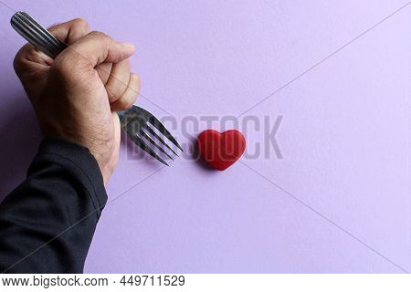 Betrayal, Disloyalty And Backstabbing Concept. Hand Stab Red Heart Using Fork.