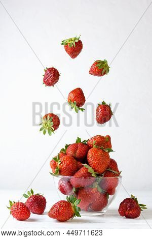 Fresh Strawberries In A Glass Bowl With Flying Berries On A White Background.
