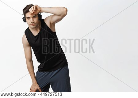 Image Of Healthy Man Workout And Listen Music In Headphones, Wipe Sweat On Forehead, Bending On Knee