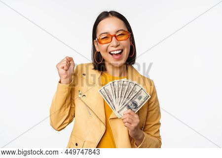 Microcredit And Money Concept. Stylish Asian Young Woman In Sunglasses, Laughing Happy, Holding Doll