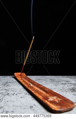 Burning Incense Stick Stands On A Wooden Stand On A Black Background.