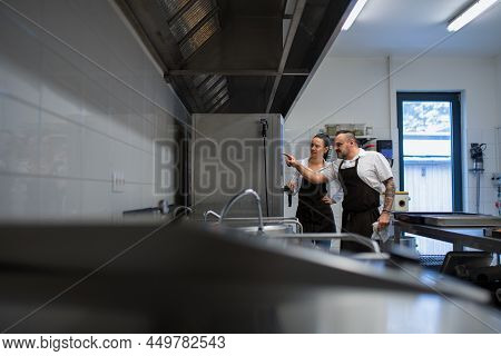 Chef Teaching Cook How To Use Combi Oven Indoors In Restaurant Kitchen.