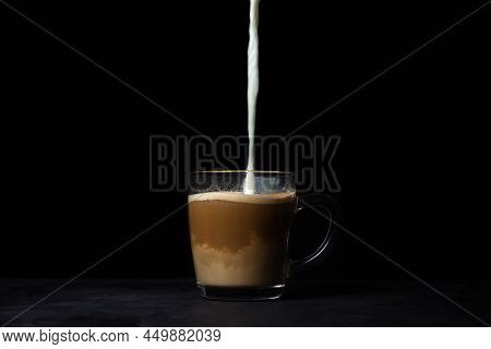 Cream Is Poured Into Coffee On A Black Background. Tonic Coffee Drink. Coffee With Milk