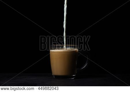 Cream Is Poured Into Coffee On A Black Background. Tonic Coffee Drink. Coffee With Milk