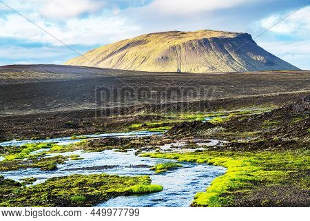 Natural Stream Flowing On The Plain In Highland In Summer Season With Green Moss Growing Along The B