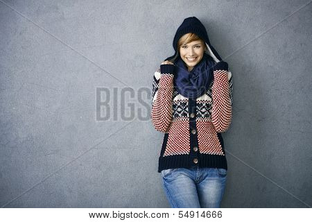 Attractive young woman wearing warm nordic sweater and hat, smiling