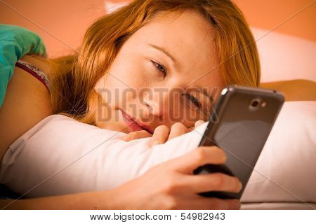 Preety Woman Reading A Sms On Cell Phone In Bed