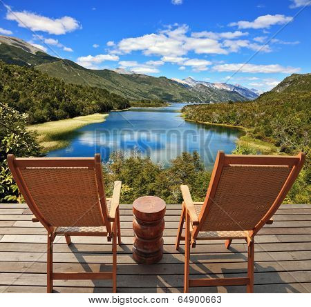Charming rural idyll. Clouds reflected in the smooth water of the river. A comfortable place to enjoy the beauty of the landscape. Two wooden chairs - on a wooden platform