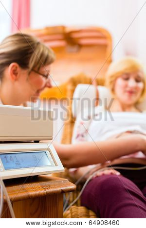 Midwife examining belly of pregnant woman with CTG scanning in practice