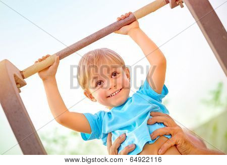 Closeup portrait of little happy boy lifting on crossbar, daddy help his son doing physical exercise outdoors, happy and healthy childhood concept