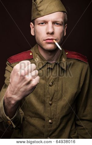 Russian soldier smoking cigarette and threaten with a fist
