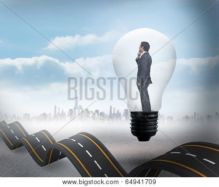Thinking businessman in light bulb against bumpy road backdrop