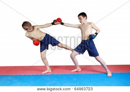 Boy in shorts and red lining hit low kick other