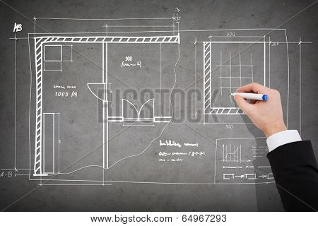 business and architecture concept - close up of businessman drawing blueprint on concrete wall