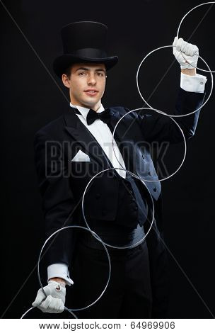magic, performance, circus, show concept - magician in top hat showing trick with linking rings