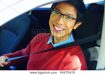 Young asian man fastening seat belt