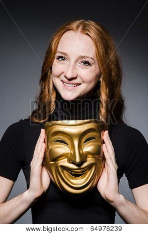 Redhead woman iwith mask in hypocrisy consept against grey background