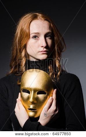 Redhead woman iwith mask in hypocrisy consept against grey background