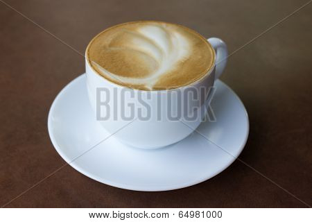Cup of art latte on a cappuccino coffee on table.