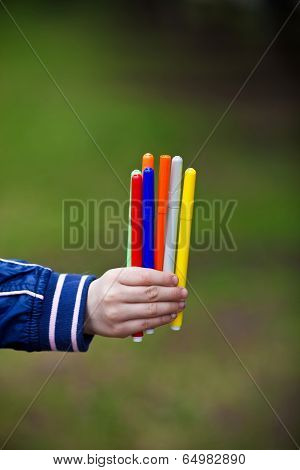 Colored markers in a child's hand on nature summer day