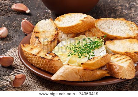 Baked Camembert cheese with thyme and toast rubbed with garlic