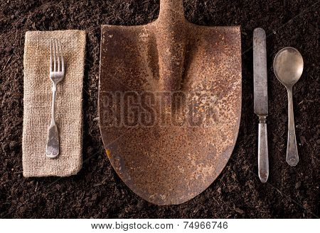 Rusted Shovel On Soil Background With Fork, Knife, Spoon, And Napkin.