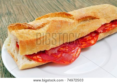closeup of a spanish bocadillo de chorizo, a chorizo sandwich, on a rustic wooden table
