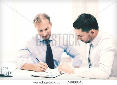 businesss concept - two businessmen discussing graphs on meeting