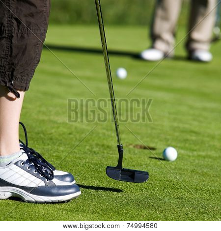 Close-up of junior golfer putting golf ball in to hole