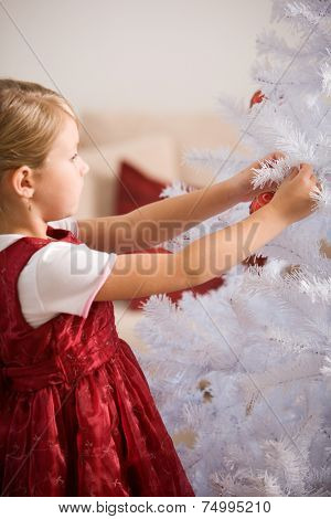 Little girl decorating white christmastree