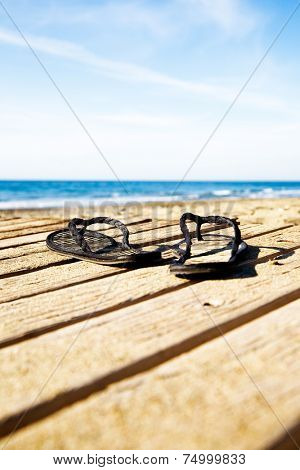 Black flipflops on the dock by the beach