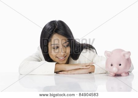 Businesswoman looking at a piggy bank