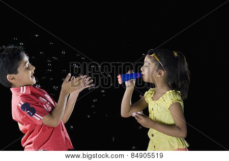 Girl blowing bubbles and a boy looking at his palm